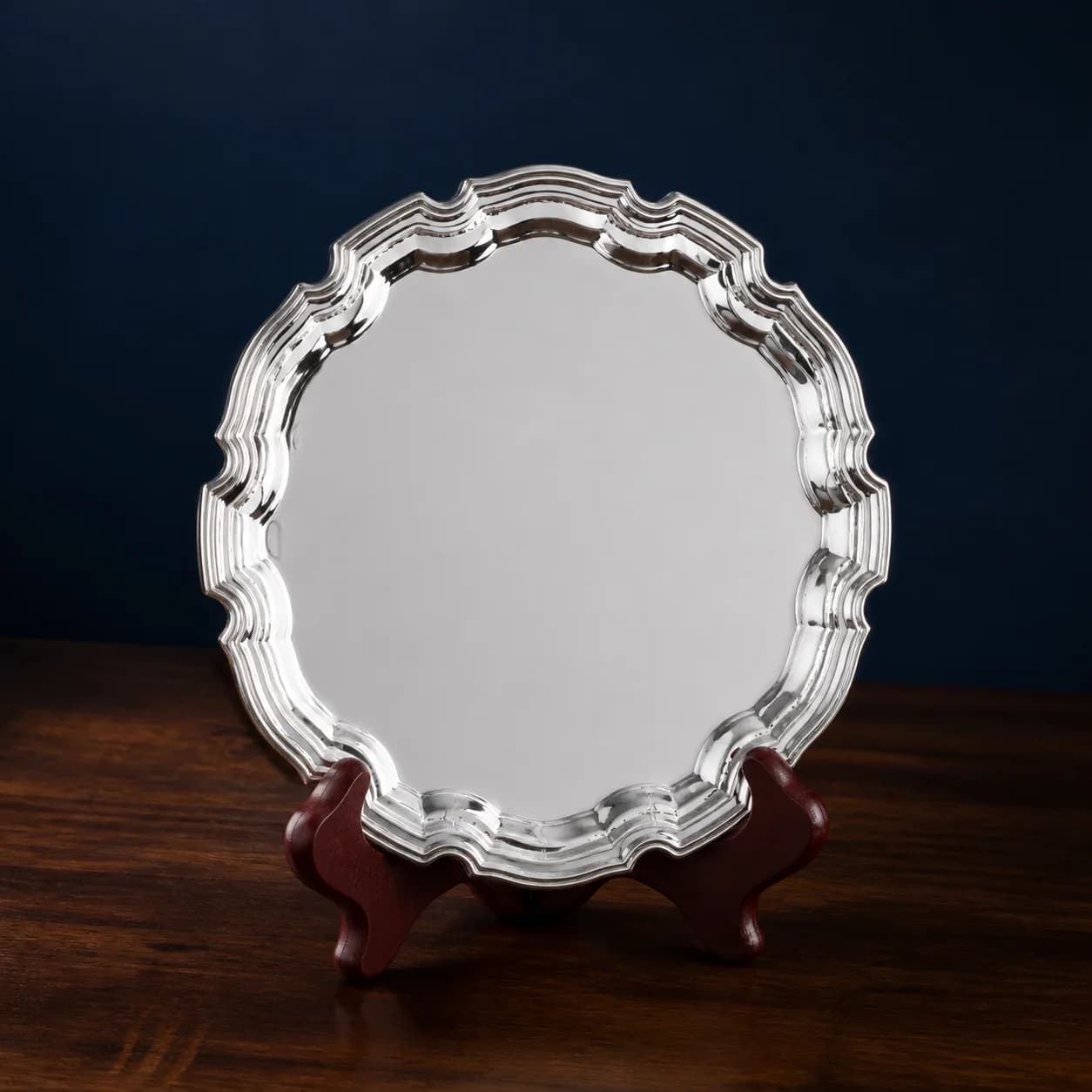 Ornate silver presentation plate displayed on a dark wooden stand