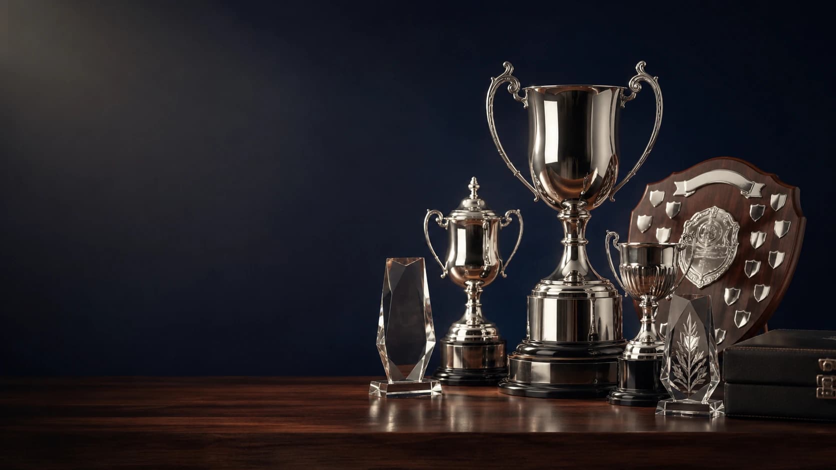 Premium trophies, crystal awards and presentation shields arranged on a dark wooden surface