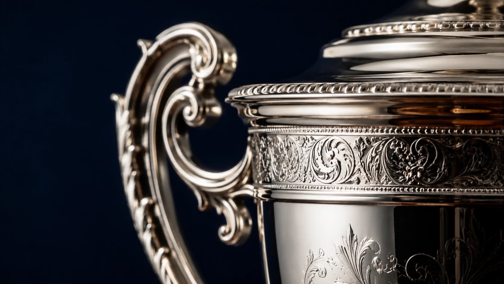 Detailed close-up of ornate engraving on a polished silver trophy